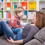 child siting on mother's lap, both laughing and talking